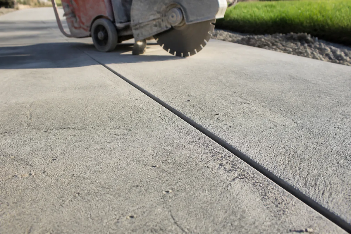 Trait de sciage rectiligne réalisé sur une dalle béton extérieure formant un joint de retrait