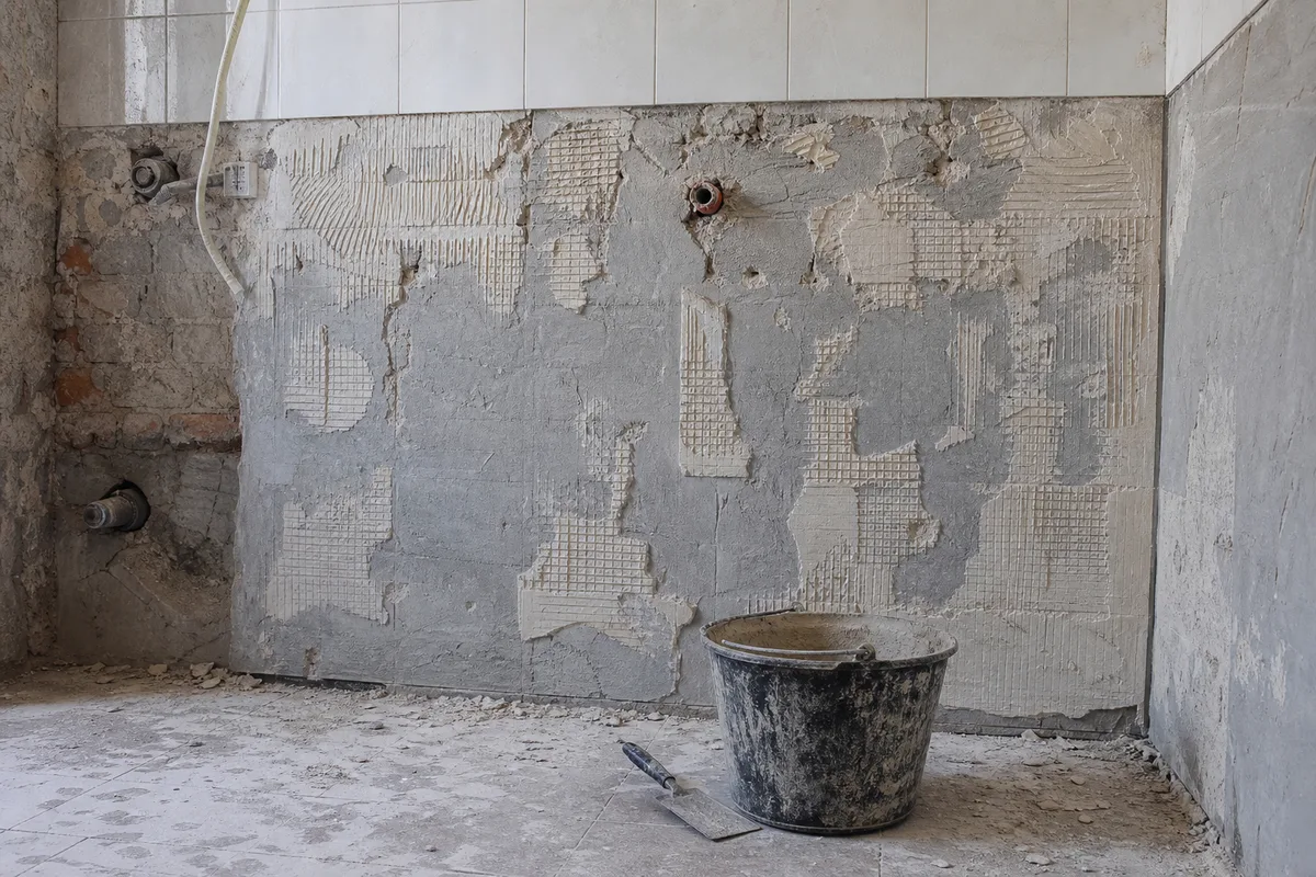 Mur de salle de bain décollé jusqu’aux briques, prêt pour la pose d’un nouveau carrelage mural