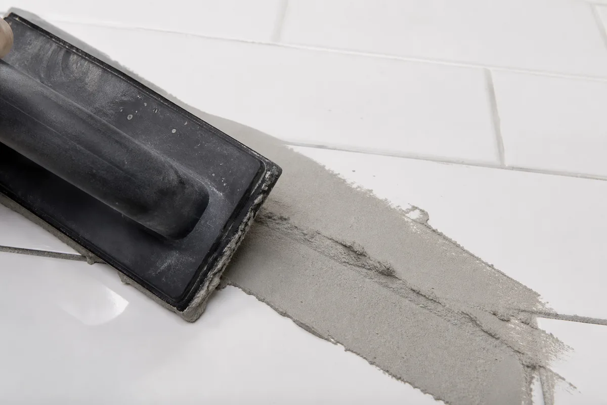 Application de joint gris à la taloche caoutchouc sur un carrelage mural fini